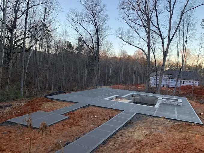 Residential construction foundation with concrete slab in wooded area during winter