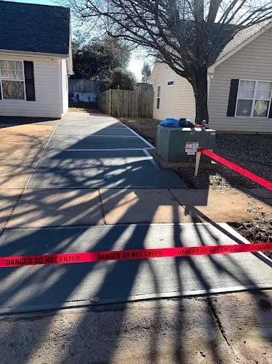 Driveway between two houses blocked by red caution tape and equipment.