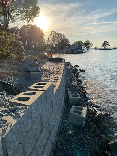 Waterfront concrete barrier with tree-lined shore and distant water landscape at sunset