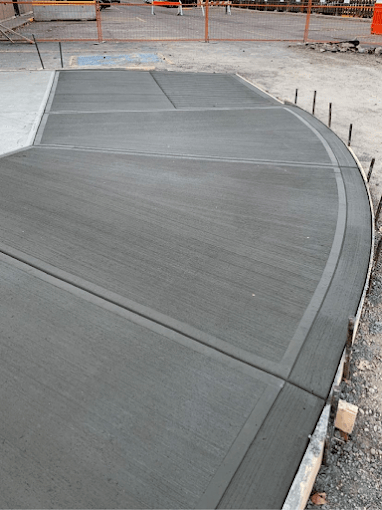 Freshly poured curved concrete surface at construction site with safety barriers