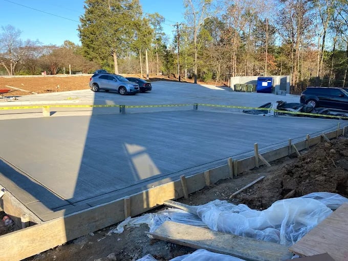 Blue concrete foundation with protective covering under construction, parked car visible